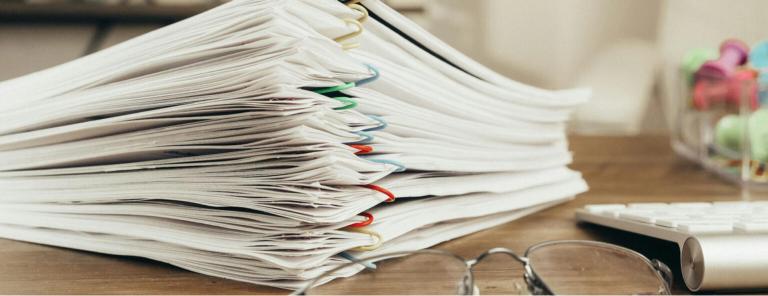 Pile of documents and paperwork on a desk, representing warranty policies.